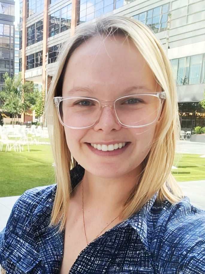 Avery wearing a blue collared shirt and glasses, smiling at the camera.