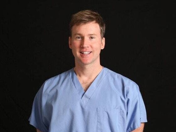 Dr. Jeff Dowis in light blue scrubs, smiling at the camera.